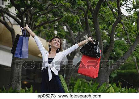 Woman with shopping bags, arms outstretched, smiling View Large Photo Image Stock Image - Woman with shopping bags, arms outstretched, smiling. Fotosearch