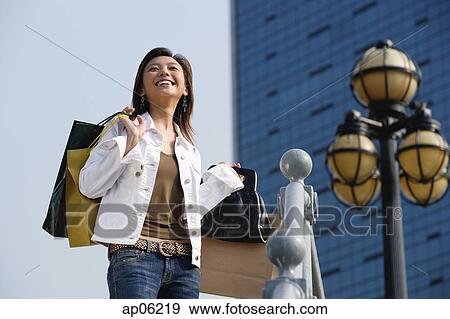 Woman with shopping bags, looking away, smiling View Large Photo Image Stock Photo - Woman with shopping bags, looking away, smiling. Fotosearch