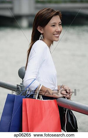 Woman with shopping bags, standing by railing View Large Photo Image Stock Photography - Woman with shopping bags, standing by railing. Fotosearch