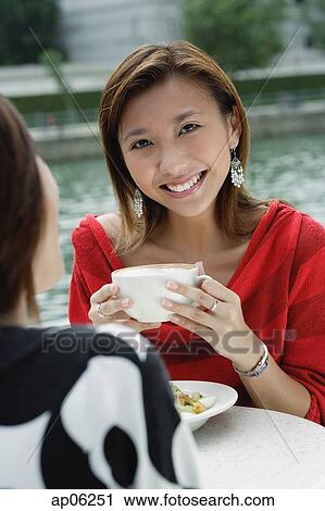 Stock Image - Women having coffee, one woman smiling at camera. Fotosearch