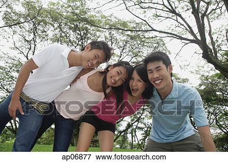 Stock Photo - Young adults in park, side by side, embracing. Fotosearch