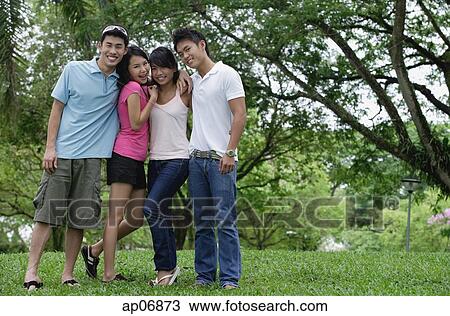 Young adults standing in park, smiling at camera View Large Photo Image Stock Image - Young adults standing in park, smiling at camera. Fotosearch