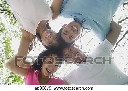 Young adults with arms around each other, looking down at camera View Large Photo Image Stock Photo - Young adults with arms around each other, looking down at camera. Fotosearch