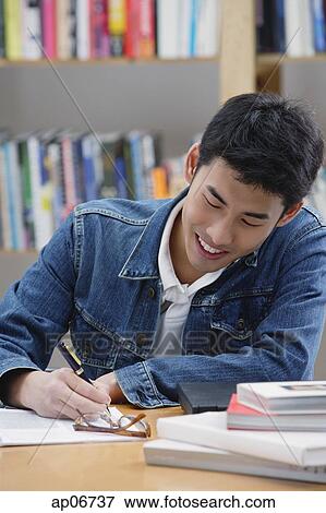 Young man in library, writing View Large Photo Image Stock Photo - Young man in library, writing. Fotosearch