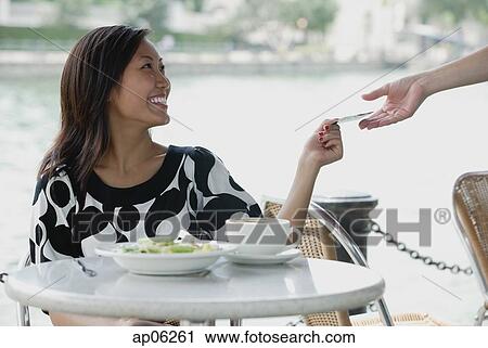 Stock Image - Young woman at cafe, paying with credit card. Fotosearch