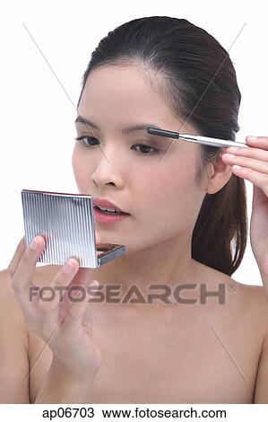 Young woman brushing eyebrows, looking at compact mirror View Large Photo Image Stock Image - Young woman brushing eyebrows, looking at compact mirror. Fotosearch