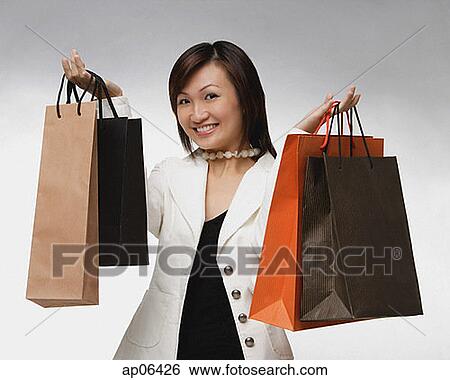 Young woman carrying shopping bags, smiling View Large Photo Image Stock Photograph - Young woman carrying shopping bags, smiling. Fotosearch