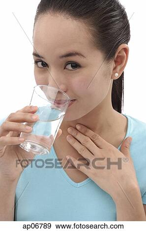 Young woman drinking from a glass of water View Large Photo Image Stock Photo - Young woman drinking from a glass of water. Fotosearch