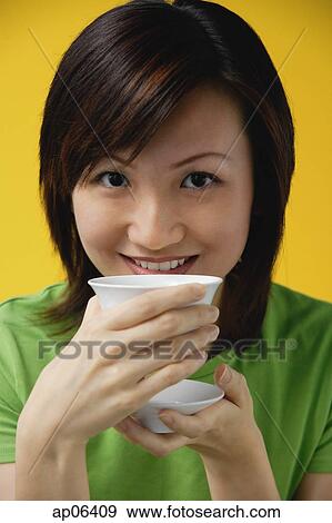 Young woman drinking from tea cup, smiling at camera View Large Photo Image Stock Photo - Young woman drinking from tea cup, smiling at camera. Fotosearch