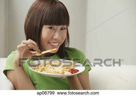 Young woman eating a plate of French fries View Large Photo Image Stock Photo - Young woman eating a plate of French fries. Fotosearch