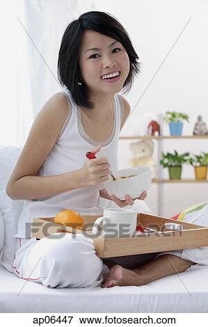 Young woman having breakfast in bed, smiling at camera View Large Photo Image Stock Photo - Young woman having breakfast in bed, smiling at camera. Fotosearch