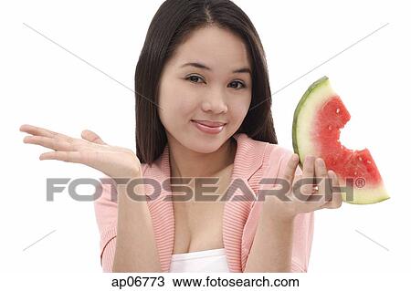 Young woman holding a slice of watermelon, looking at camera View Large Photo Image Stock Image - Young woman holding a slice of watermelon, looking at camera. Fotosearch