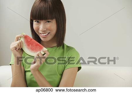 Stock Image - Young woman holding a slice of watermelon. Fotosearch