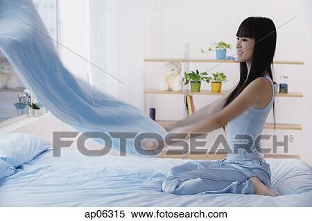 Young woman holding blanket, making the bed View Large Photo Image Stock Photography - Young woman holding blanket, making the bed. Fotosearch