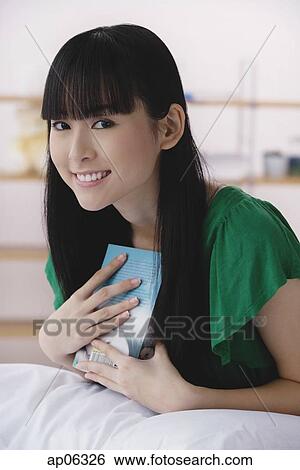 Young woman holding book, smiling View Large Photo Image Stock Photograph - Young woman holding book, smiling. Fotosearch