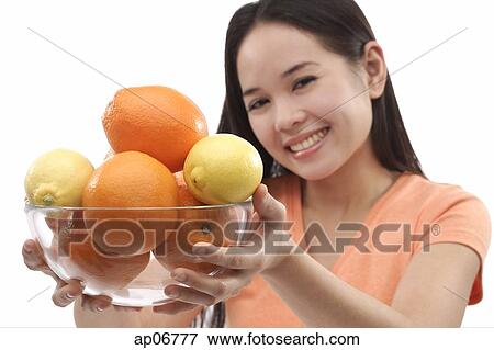 Young woman holding bowl of oranges and lemons towards camera View Large Photo Image Stock Photo - Young woman holding bowl of oranges and lemons towards camera. Fotosearch