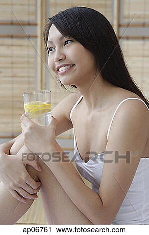 Young woman holding glass of water, hugging knees, looking away View Large Photo Image Stock Image - Young woman holding glass of water, hugging knees, looking away. Fotosearch