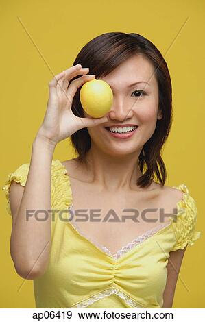 Young woman holding lemon over her eye, portrait View Large Photo Image Stock Photo - Young woman holding lemon over her eye, portrait. Fotosearch
