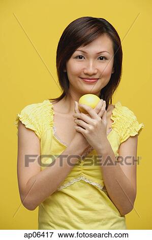 Young woman holding lemon, standing against yellow background View Large Photo Image Stock Photo - Young woman holding lemon, standing against yellow background. Fotosearch