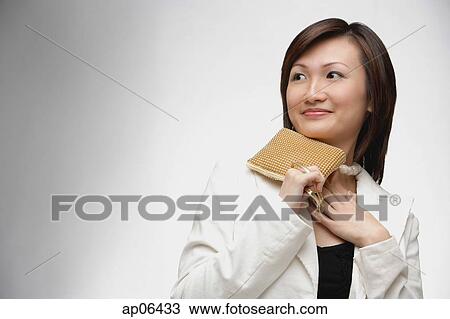 Young woman holding purse, looking away View Large Photo Image Stock Image - Young woman holding purse, looking away. Fotosearch
