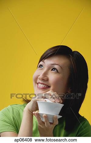 Young woman holding teacup, looking away View Large Photo Image Stock Photo - Young woman holding teacup, looking away. Fotosearch