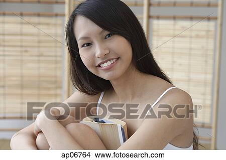 Young woman hugging knees, smiling View Large Photo Image Picture - Young woman hugging knees, smiling. Fotosearch