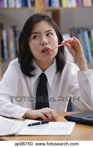 Young woman in library, biting pen, looking way View Large Photo Image Stock Image - Young woman in library, biting pen, looking way. Fotosearch