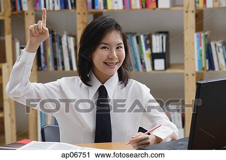 Young woman in library, hand raised, smiling View Large Photo Image Stock Image - Young woman in library, hand raised, smiling. Fotosearch