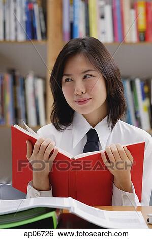 Young woman in library, holding book, looking away View Large Photo Image Stock Photograph - Young woman in library, holding book, looking away. Fotosearch