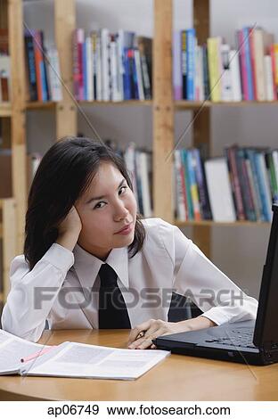 Young woman in library, leaning on hand, looking at camera View Large Photo Image Stock Photo - Young woman in library, leaning on hand, looking at camera. Fotosearch