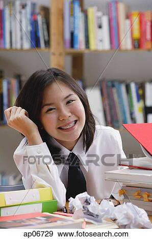 Young woman in library, surrounded by books and crumpled paper View Large Photo Image Stock Photo - Young woman in library, surrounded by books and crumpled paper. Fotosearch