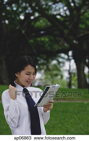 Stock Image - Young woman in school uniform, reading a book. Fotosearch