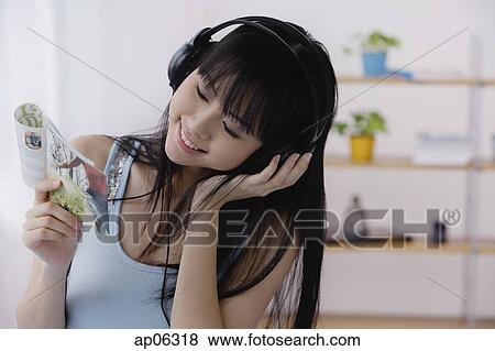 Stock Photo - Young woman listening to music and looking at CDs. Fotosearch