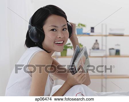 Young woman listening to music, smiling, head shot View Large Photo Image Picture - Young woman listening to music, smiling, head shot. Fotosearch