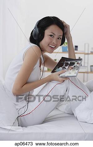Young woman listening to music, smiling View Large Photo Image Stock Image - Young woman listening to music, smiling. Fotosearch