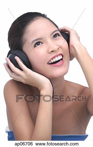 Stock Photograph - Young woman listening to music, wearing headphones. Fotosearch