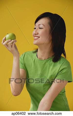 Young Woman looking at apple View Large Photo Image Stock Image - Young Woman looking at apple. Fotosearch