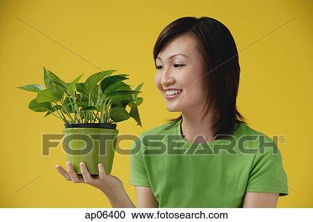 Stock Image - Young Woman looking at plant. Fotosearch