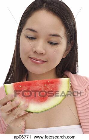 Young woman looking at slice of watermelon View Large Photo Image Stock Image - Young woman looking at slice of watermelon. Fotosearch