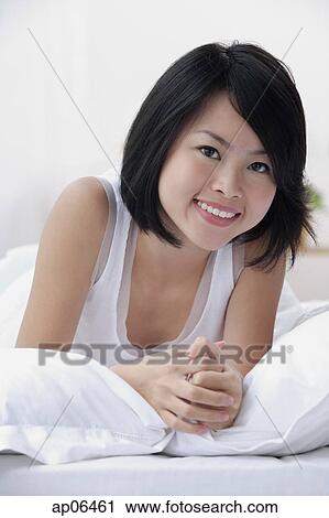 Young woman on bed, smiling at camera View Large Photo Image Stock Image - Young woman on bed, smiling at camera. Fotosearch