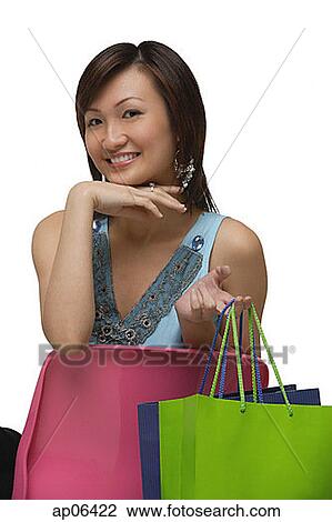 Young woman sitting on pink chair, holding shopping bags, portrait View Large Photo Image Stock Image - Young woman sitting on pink chair, holding shopping bags, portrait. Fotosearch