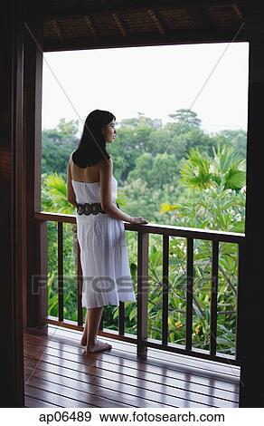 Young woman standing on balcony View Large Photo Image Stock Photo - Young woman standing on balcony. Fotosearch