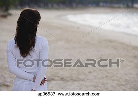 Young woman standing on beach, rear view View Large Photo Image Stock Photo - Young woman standing on beach, rear view. Fotosearch