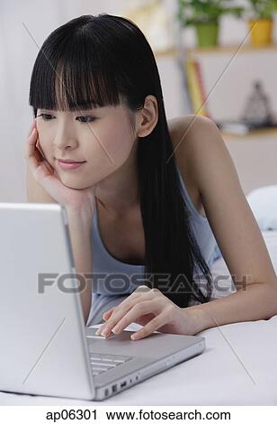 Young woman using laptop, hand on chin View Large Photo Image Stock Image - Young woman using laptop, hand on chin. Fotosearch