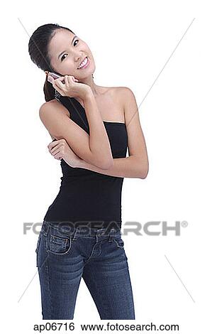 Stock Photograph - Young woman using mobile phone, smiling at camera. Fotosearch