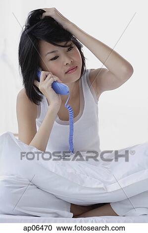 Young woman using telephone, hand on head View Large Photo Image Stock Image - Young woman using telephone, hand on head. Fotosearch