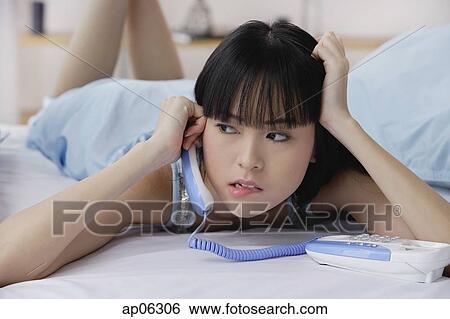 Young woman using telephone, hand on head, biting lip View Large Photo Image Stock Photograph - Young woman using telephone, hand on head, biting lip. Fotosearch