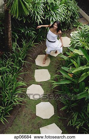 Young woman walking in tropical garden, smiling at camera View Large Photo Image Picture - Young woman walking in tropical garden, smiling at camera. Fotosearch
