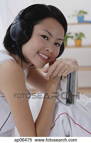 Young woman wearing earphones, smiling at camera View Large Photo Image Stock Photography - Young woman wearing earphones, smiling at camera. Fotosearch