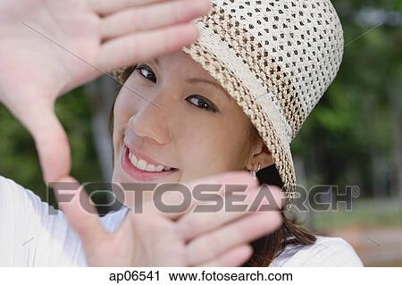 Stock Image - Young woman wearing hat, making finger frame. Fotosearch